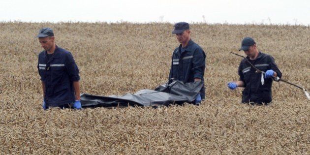 Ukrainian rescue workers carry the body of a victim on a stretcher through a wheat field at the site of the crash of a Malaysia Airlines plane carrying 298 people from Amsterdam to Kuala Lumpur in Grabove, in rebel-held east Ukraine, on July 19, 2014. Ukraine and pro-Russian insurgents agreed on July 19 to set up a security zone around the crash site of a Malaysian jet whose downing in the rebel-held east has drawn global condemnation of the Kremlin. Outraged world leaders have demanded Russia's immediate cooperation in a prompt and independent probe into the shooting down on July 17 of flight MH17 with 298 people on board. AFP PHOTO / DOMINIQUE FAGET (Photo credit should read DOMINIQUE FAGET/AFP/Getty Images)