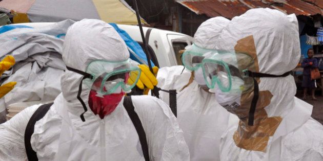 Health workers in protective gear leave after carrying the body of a woman that they suspect died from the Ebola virus, in an area known as Clara Town in Monrovia, Liberia, Wednesday, Sept. 10, 2014. A surge in Ebola infections in Liberia is driving a spiraling outbreak in West Africa that is increasingly putting health workers at risk as they struggle to treat an overwhelming number of patients. A higher proportion of health workers has been infected in this outbreak than in any previous one. (AP Photo/Abbas Dulleh)