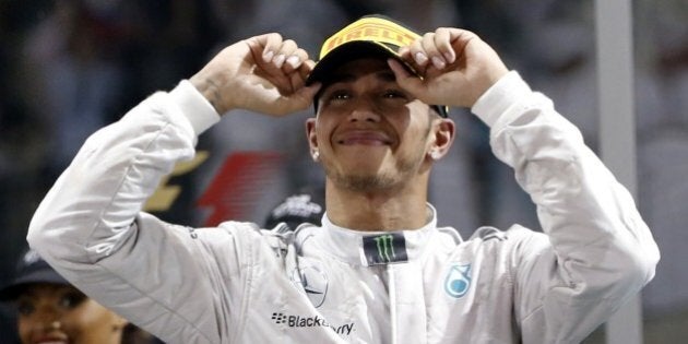 Mercedes-AMG's British driver Lewis Hamilton celebrates on the podium at the Yas Marina circuit in Abu Dhabi on November 23, 2014 after the Abu Dhabi Formula One Grand Prix. AFP PHOTO / KARIM SAHIB (Photo credit should read KARIM SAHIB/AFP/Getty Images)