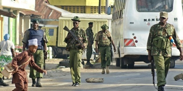 A Muslim schoolboy runs across a road past approaching police officers on patrol around the Masjid Swafaa mosque in the district of Kisauni in Kenya's coastal town of Mombasa following a raid on November 19, 2014. Kenyan security forces carried out fresh raids on a mosque in the port city of Mombasa searching for weapons and supporters of Somalia's Shebab militants, police said. Grenades, ammunition and petrol bombs were seized in the raid on the Swafaa mosque, the third to be searched this week in the tense city, officers said. AFP PHOTO/STRINGER (Photo credit should read STRINGER/AFP/Getty Images)