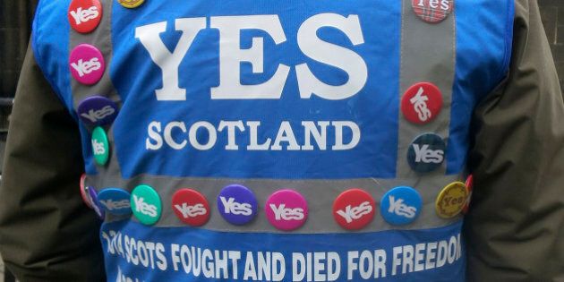 In this photo taken March 15, 2014 a man wears a multitude of 'yes' campaign badges during a pro-independence march in Edinburgh, Scotland for the upcoming vote on Scotland's independence from the United Kingdom. Scotland's swithering