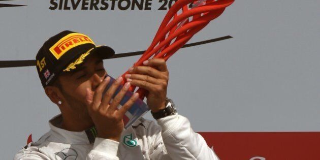 Mercedes-AMG's British driver Lewis Hamilton celebrates on the podium at the Silverstone circuit in Silverstone on July 6, 2014 after the British Formula One Grand Prix. AFP PHOTO / DIMITAR DILKOFF (Photo credit should read DIMITAR DILKOFF/AFP/Getty Images)