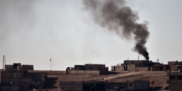 Smoke rises from the central part of the Syrian town of Ain al-Arab, known as Kobane by the Kurds, as seen from the Turkish-Syrian border, as a Kurdish flag waves during heavy fighting, in the southeastern town of Suruc, Sanliurfa province, on October 7, 2014. Pro-Kurdish protesters clashed overnight on October 7 with police in several Turkish cities, including Istanbul, in a show of anger against the lack of action by the government against jihadists fighting for a key Syrian town. AFP PHOTO / ARIS MESSINIS (Photo credit should read ARIS MESSINIS/AFP/Getty Images)