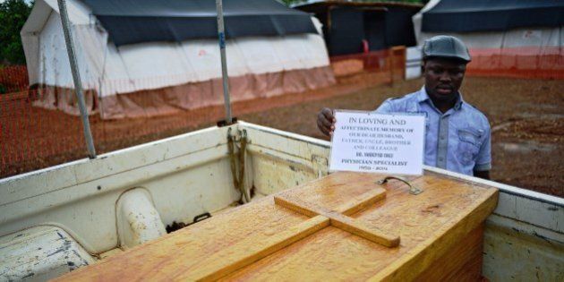 A man stands next to the coffin of Dr Modupeh Cole, Sierra Leone's second senior physician to die of Ebola, at the Medecins Sans Frontieres (MSF) facility in Kailahun, on August 14, 2014. Kailahun along with Kenama district is at the epicentre of the world's worst Ebola outbreak. The World Health Organisation (WHO) revealed that the latest death toll from the Ebola virus in Guinea, Sierra Leone, Liberia and Nigeria had claimed more than 1000 lives. Health Organisations are looking into the possible use of experimental drugs to combat the latest outbreak in West Africa. AFP PHOTO / CARL DE SOUZA (Photo credit should read CARL DE SOUZA/AFP/Getty Images)
