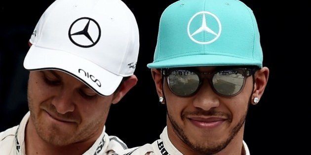 Mercedes AMG Petronas F1 Team's British driver Lewis Hamilton (R) gestures after taking pole position while teammate Mercedes AMG Petronas F1 Team's German driver Nico Rosberg (L) looks on following the qualifying race at the Formula One Malaysian Grand Prix in Sepang on March 28, 2015. AFP PHOTO / MANAN VATSYAYANA (Photo credit should read MANAN VATSYAYANA/AFP/Getty Images)