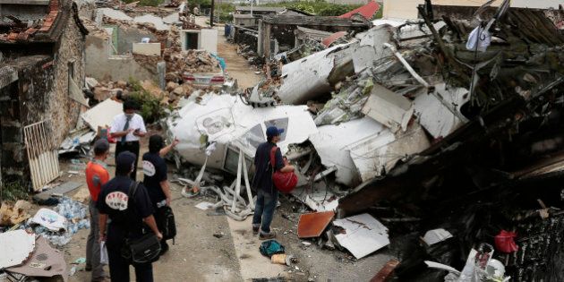 PENGHU ISLAND, TAIWAN - JULY 24: Criminal Investigation Bureau search through the crash site where TransAsia Airways flight GE222 crashed the night before near the airport at Magong on July 24, 2014 in Penghu Island, Taiwan. Taiwan's TransAsia Airways crashed in the Penghu Islands killing 47 of the 58 people on board when it went down amid heavy rain yesterday. (Photo by Ashley Pon/Getty Images)