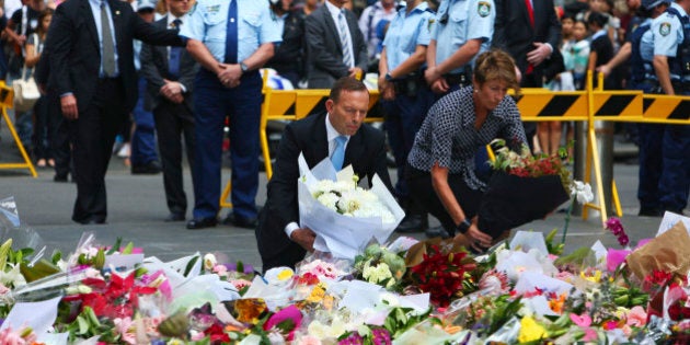 Australian Prime Minister Tony Abbott and his wife Margie pay their respect to the victims of the siege in Martin Place in Sydney central business district, Australia. Tuesday, Dec. 16, 2014. Abbott has laid flowers at a makeshift memorial in Sydney for the victims of a central city cafe siege which left three people dead. (Photo: Steve Christo)