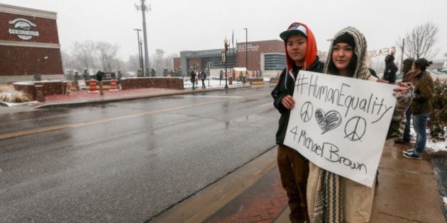 FERGUSON, UNITED STATES - NOVEMBER 26: People hold banners reading 'Human Equality' as National Guard troopers patrol at the police station in Ferguson, Missouri, United States on November 26,2014. The Ferguson Grand Jury decision about Officer Daren Wilson is that he will not be faced with criminal charges for the shooting death of black 18-year old Michael Brown in Ferguson. (Photo by Cem Ozdel/Anadolu Agency/Getty Images)
