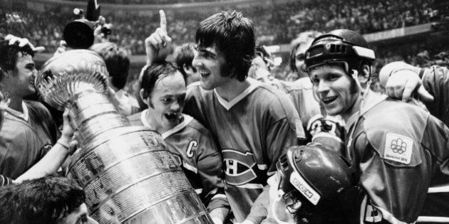Yvan Cournoyer, captain of the Montreal Canadiens, holds the Stanley Cup as he is surrounded by teammates in Philadelphia, Pa., Sunday night, May 16, 1976. Montreal beat the Philadelphia Flyers to take the final series of the cup. (AP Photo)