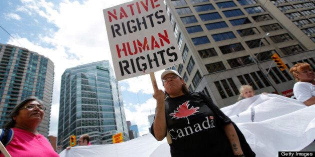 TORONTO, ON - JUNE 24: A woman holds a sign as several hundred indigenous people march through the streets of Toronto to bring attention to the plight of indigenous peoples in Canada two days prior to the opening of the G20 Summit on June 24, 2010 in Toronto, Canada. Leaders from the world's 20 largest industrial and developing nations are arriving in Toronto for the G20 Summit scheduled to be held June 26 and 27. (Photo by Jemal Countess/Getty Images)
