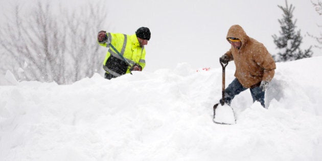 Mark Settlemyer, left, gets help clearing snow from the roof of his mother's house from Ken Wesley on Wednesday, Nov. 19, 2014, in Lancaster, N.Y. Lake-effect snow pummeled areas around Buffalo for a second straight day, leaving residents stuck in their homes as officials tried to clear massive snow mounds with another storm looming. (AP Photo/Mike Groll)