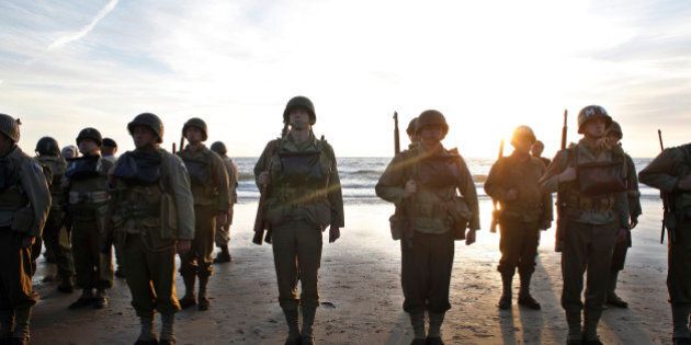 A group of military enthusiasts stand on Omaha Beach in Vierville sur Mer, western France , Friday June 6, 2014. World leaders and dignitaries including President Barack Obama and Queen Elizabeth II will gather to honor the more than 150,000 American, British, Canadian and other Allied D-Day troops who risked and gave their lives to defeat Adolf Hitler's Third Reich. (AP Photo/Thibault Camus)