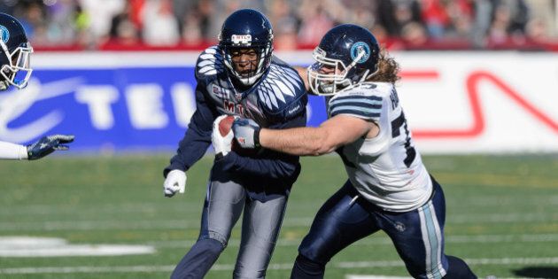 MONTREAL, QC - NOVEMBER 2: Logan Harrell #77 of the Toronto Argonauts tackles Duron Carter #89 of the Montreal Alouettes during the CFL game at Percival Molson Stadium on November 2, 2014 in Montreal, Quebec, Canada. (Photo by Minas Panagiotakis/Getty Images)