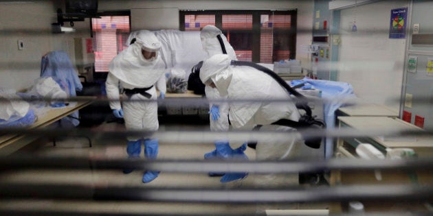 FILE- In this Oct. 24, 2014 file photo, members of the Department of Defense's Ebola Military Medical Support Team dress with protective gear during training at San Antonio Military Medical Center in San Antonio. Even small clusters of Ebola cases could overwhelm parts of US medical care system, according to an Associated Press review of readiness at hospitals and other components of the emergency medical network. (AP Photo/Eric Gay, File)