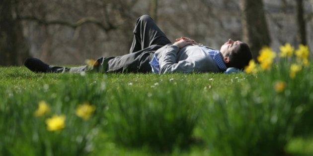 A man lies in the sun in St James's Park, London, as Londoners enjoy the warm weather.