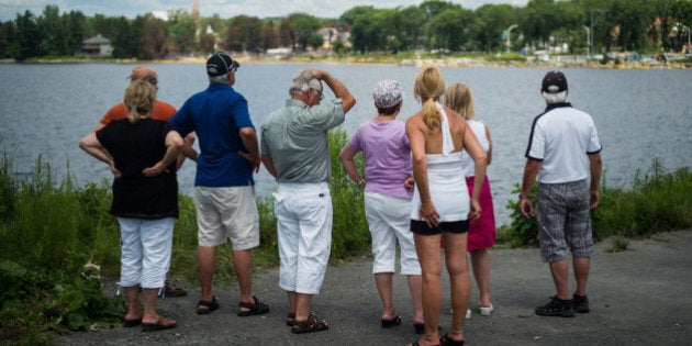 LAC-MEGANTIC, CANADA - JULY 14: People look out toward the 'red zone' crash site, on July 14, 2013 in Lac-Megantic, Quebec, Canada. A train derailed and exploded into a massive fire that flattened dozens of buildings in the town's historic district, leaving 60 people dead or missing in the early morning hours of July 6. (Photo by Ian Willms/Getty Images)