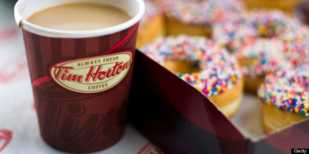 A cup of Tim Hortons Inc. coffee and doughnuts are arranged for a photograph in Toronto, Ontario, Canada, on Wednesday, Aug. 3, 2011. Tim Hortons Inc. is a chain of franchise fast food restaurants that serve coffee drinks, tea, soups, sandwiches, donuts, bagels, and pastries. Photographer: Brent Lewin/Bloomberg via Getty Images