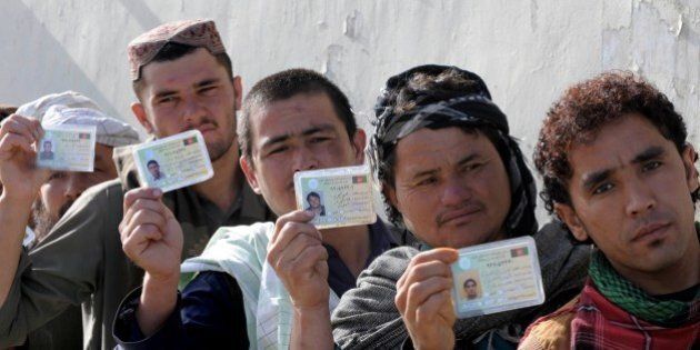 Afghan voters display their national identity cards as they queue to cast their votes at a local polling station in Kandahar on April 5, 2014. Afghan voters went to the polls to choose a successor to President Hamid Karzai, braving Taliban threats in a landmark election held as US-led forces wind down their long intervention in the country. AFP PHOTO/Banaras KHAN (Photo credit should read BANARAS KHAN/AFP/Getty Images)