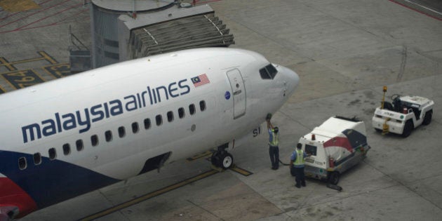 Workers inspect a Malaysia Airlines plane on the tarmac at Kuala Lumpur International Airport (KLIA) in Sepang on March 13, 2014. Planes searching an area where Chinese satellites spotted possible debris from missing Malaysia Airlines flight MH370 have found no sign of wreckage, officials said on March 13, dimming hopes of a breakthrough in the mystery. AFP PHOTO / MOHD RASFAN (Photo credit should read MOHD RASFAN/AFP/Getty Images)