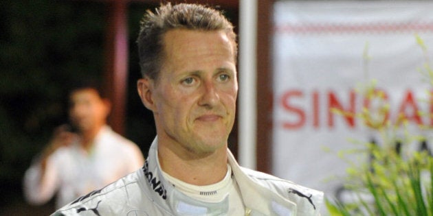 Mercedes AMG Petronas driver Michael Schumacher (L) of Germany walks back to the paddock after crashing out of Formula One's Singapore Grand Prix on September 23, 2012. AFP PHOTO / ROSLAN RAHMAN (Photo credit should read ROSLAN RAHMAN/AFP/GettyImages)