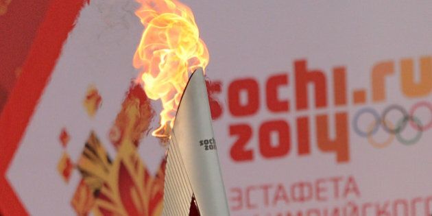 One of the Olympic torches rises in front of a poster with the Sochi 2014 Winter Olympic logo just outside the Red Square in Moscow, on October 7, 2013, during a ceremony to kick off the Sochi 2014 Winter Olympic torch relay across Russia. AFP PHOTO / KIRILL KUDRYAVTSEV (Photo credit should read KIRILL KUDRYAVTSEV/AFP/Getty Images)