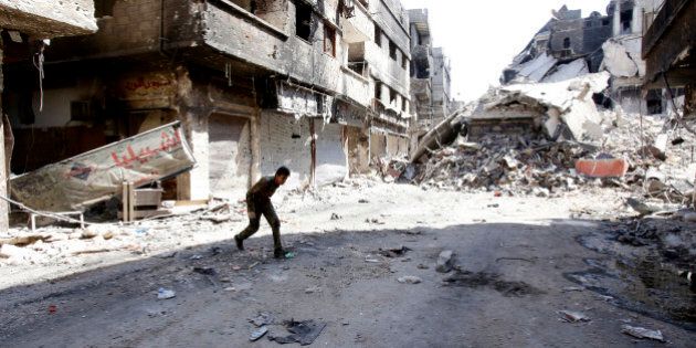 A fighter of the Popular Front for the Liberation of Palestine General Command (PFLP-GC) runs across a street in the Yarmouk refugee camp in the Syrian capital Damascus on September 12, 2013, following fighting against rebel forces who control 75 percent of the camp. The PFLP-GC has been allied to Syrian President Bashar al-Assad's government whose troops have been fighting rebel forces for the past two years. AFP PHOTO/ANWAR AMRO (Photo credit should read ANWAR AMRO/AFP/Getty Images)