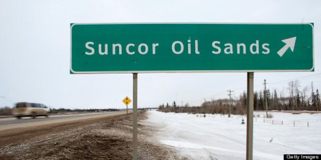 A sign directing traffic to the Suncor Energy Inc. base plant stands at the Athabasca Oil Sands near Fort McMurray, Alberta, Canada, on Tuesday, March 26, 2013. Canadian light oil prices retreated from a six-month high on the spot market reached last week as production slipped and refineries prepared for maintenance. Photographer: Brett Gundlock/Bloomberg via Getty Images
