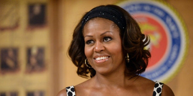 US First Lady Michelle Obama smiles as President Barack Obama talks to members of the military and their families during a Christmas dinner in Anderson Hall at Marine Corps Base Hawaii in Kaneohe Bay, Hawaii, on December 25, 2013. The first family is in Hawaii for their annual holiday vacation. AFP PHOTO/Jewel SAMAD (Photo credit should read JEWEL SAMAD/AFP/Getty Images)