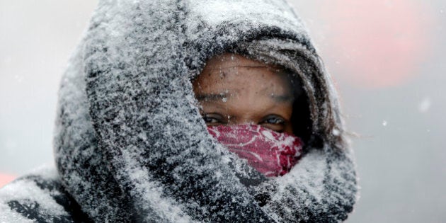 A woman stands at the entrance of a building during a winter snowstorm Tuesday, Jan. 21, 2014, in Philadelphia. A storm is sweeping across the Mid-Atlantic and New England. The National Weather Service said the storm could bring 8 to 12 inches of snow to Philadelphia and New York City, and more than a foot in Boston. (AP Photo/Matt Rourke)