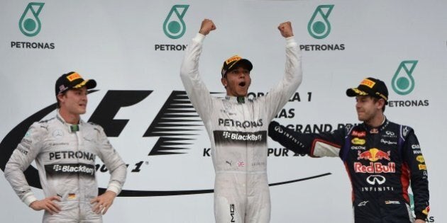 Mercedes driver Lewis Hamilton of Britain (C) celebrates his victory on the podium as second-placed Mercedes driver Nico Rosberg (L) and third-placed Red Bull driver Sebastian Vettel (R) look on at the awards ceremony after the Formula One Malaysian Grand Prix at the Sepang circuit near Kuala Lumpur on March 30, 2014. AFP PHOTO / ROSLAN RAHMAN (Photo credit should read ROSLAN RAHMAN/AFP/Getty Images)