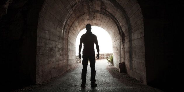 young man stands in dark tunnel ...