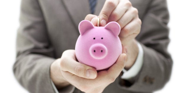 Businessman putting coin into the piggy bank