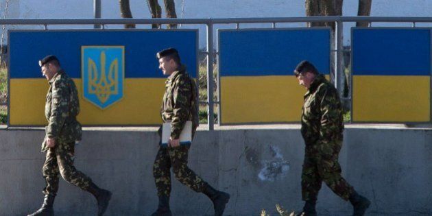 Russian officers walk past the Ukrainian marine battalion headquarters in the Crimean city of Feodosia on March 23, 2014. Ukraine's Western-backed leaders voiced fears on Sunday of an imminent Russian invasion of the eastern industrial heartland following the fall of their last airbase in Crimea to defiant Kremlin troops. AFP PHOTO/ DMITRY SEREBRYAKOV (Photo credit should read DMITRY SEREBRYAKOV/AFP/Getty Images)