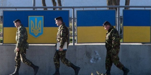 Russian officers walk past the Ukrainian marine battalion headquarters in the Crimean city of Feodosia on March 23, 2014. Ukraine's Western-backed leaders voiced fears on Sunday of an imminent Russian invasion of the eastern industrial heartland following the fall of their last airbase in Crimea to defiant Kremlin troops. AFP PHOTO/ DMITRY SEREBRYAKOV (Photo credit should read DMITRY SEREBRYAKOV/AFP/Getty Images)