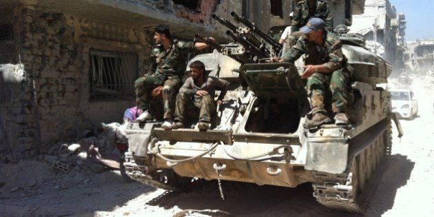 A picture taken on July 29, 2013 shows soldiers loyal to the regime forces sitting on a tank as they patrol in a devastated street of the district of al-Khalidiyah, in the central Syrian city of Homs. Seven children in the northern Syrian province of Aleppo and another four in Homs in the centre were among 17 civilians killed in air raids on July 30, 2013, a watchdog said. AFP PHOTO SAM SKAINE (Photo credit should read SAM SKAINE/AFP/Getty Images)