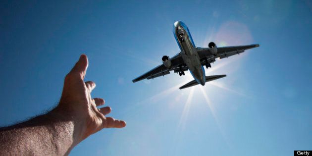 Hand reaching for aeroplane in sky
