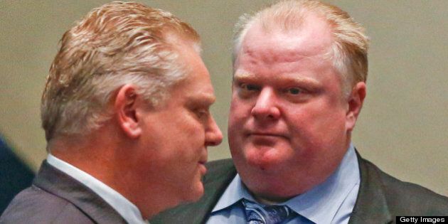 TORONTO, ON - FEBRUARY 20: Councillor Doug Ford and Mayor Rob Ford chat in council chambers during a discussion on a motion by councillor Adam Vaughn to open up the debate on city shelters, which was later voted down. (Bernard Weil/Toronto Star via Getty Images)