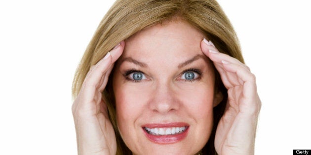 Headshot of a mature woman stretching her skin and smiling