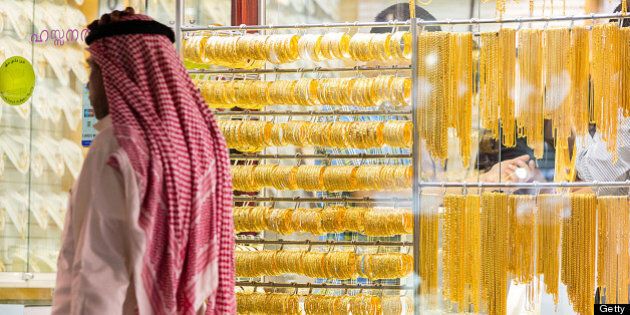 A pedestrian passes gold jewelry on display in the windows of a gold store in the Dubai Gold Souk in the Deira district of Dubai, United Arab Emirates, on Tuesday, July 2, 2013. Gold swung between gains and losses in London as investors weighed prospects for increased physical demand against a slowing stimulus in the U.S. Photographer: Duncan Chard/Bloomberg via Getty Images