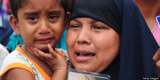 A Bangladeshi woman and her daughter weep as she holds up the portrait of her missing husband, believed to be trapped in the rubble of an eight-storey building collapse in Savar, on the outskirts of Dhaka, on April 30, 2013. Bangladesh on Tuesday defended its decision to snub foreign aid after the collapse of a factory complex as anger flared at the recovery operation and towards the building's owner when he appeared in court, with the death toll from the country's worst ever industrial disaster now standing at 387. AFP PHOTO/MUNIR UZ ZAMAN (Photo credit should read MUNIR UZ ZAMAN/AFP/Getty Images)