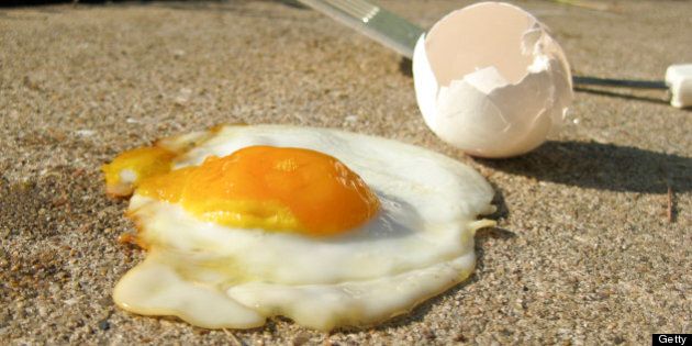 fried egg on sidewalk with spatula and broken eggshell on a hot summer day
