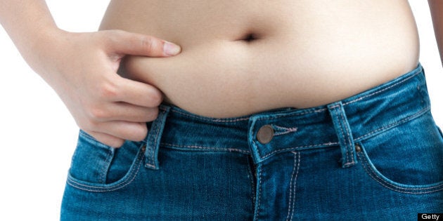 A Woman Wearing Blue Jeans Pinches Her Belly Fat