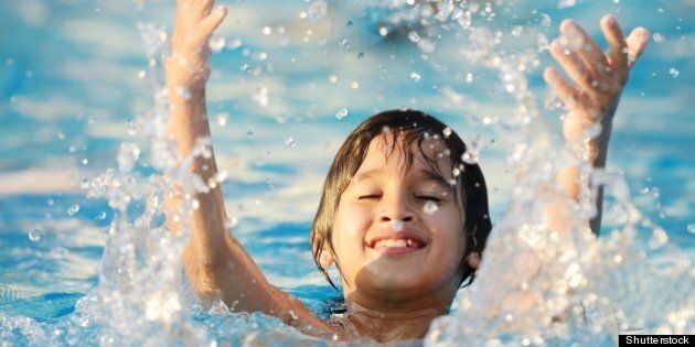 kid splashing on summer pool