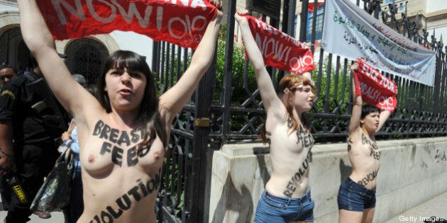 Three activists from the Femen feminist group, demonstrate in front of the justice Palace in Tunis, on May 29, 2013, before being arrested. The women, two French and the other German, shouted: 'Free Amina,' in reference to the young Tunisian woman imprisoned for protesting against hardline Islamists and awaiting trial for illegally possessing pepper spray. AFP PHOTO / FETHI BELAID (Photo credit should read FETHI BELAID/AFP/Getty Images)