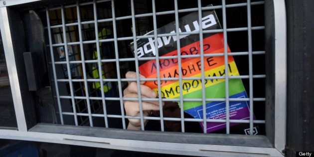 A Russian gay and LGBT rights activist shows sign reading 'Love is stronger than homophobia' from inside of a Russian riot police van during unauthorized gay rights activists rally in cental Moscow on May 25, 2013. AFP PHOTO/KIRILL KUDRYAVTSEV (Photo credit should read KIRILL KUDRYAVTSEV/AFP/Getty Images)