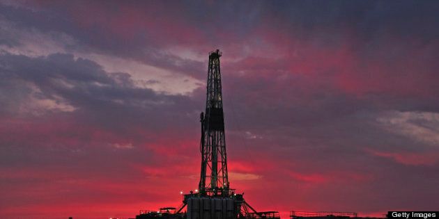 A silhouette shot of a drilling rig at sunset.