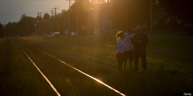 LAC-MEGANTIC QC - JULY 8: Bystanders reviewed photographs beside the tracks on the perimeter of the crash site as the sun set Monday night in Lac-MÈgantic. (Lucas Oleniuk/Toronto Star via Getty Images)