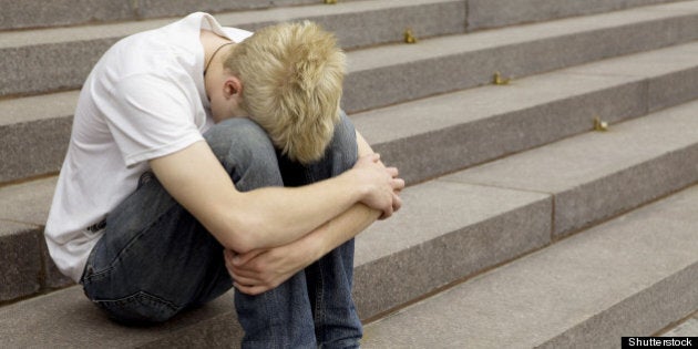 upset young blond man sitting...