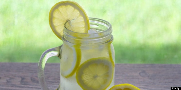 Refreshing glass of ice cold lemonade with a slice of lemon on the side of the glass.