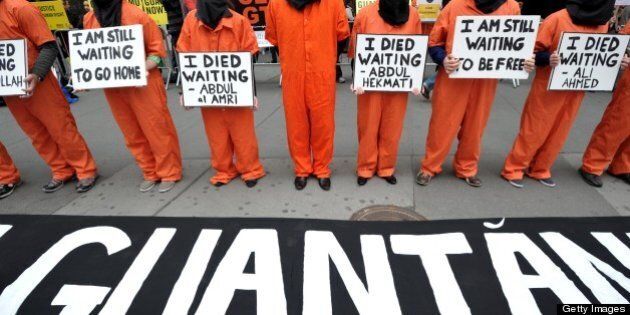 People dress in orange jumpsuits and black hoods as activists demand the closing of the US military's detention facility in Guantanamo during a protest, part of the Nationwide for Guantanamo Day of Action, April 11, 2013 in New York's Times Square. The Guantanamo jail, in a US Navy base in Cuba, was opened in 2002 to hold prisoners taken in the 'War on Terror' waged by then US President George W. Bush after the 9/11 attacks. AFP PHOTO/Stan HONDA (Photo credit should read STAN HONDA/AFP/Getty Images)